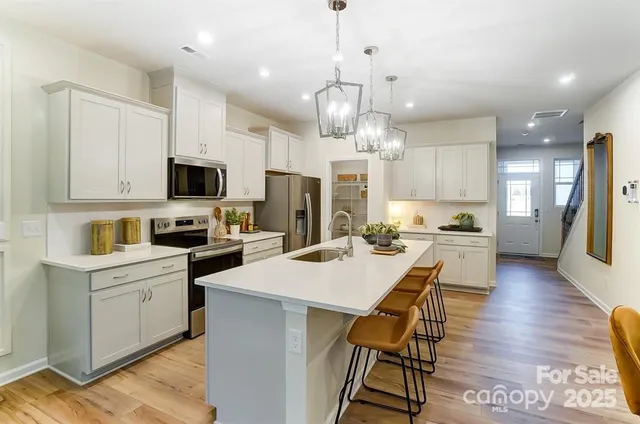 a kitchen with stainless steel appliances kitchen island granite countertop a sink a stove a refrigerator cabinets and chairs