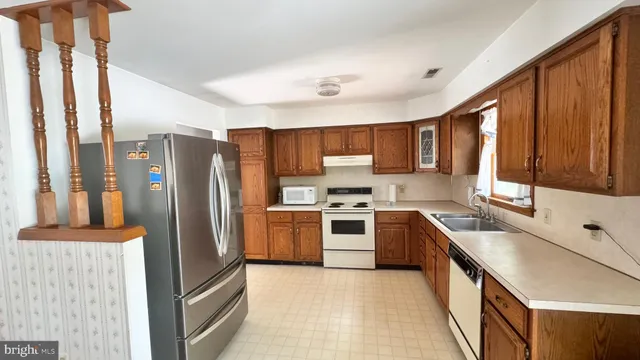 a kitchen with stainless steel appliances granite countertop a refrigerator a sink a stove and a cabinets