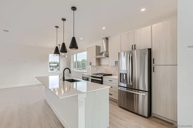 a kitchen with stainless steel appliances a refrigerator a sink a stove and a center island