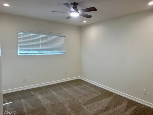 an empty room with a window and ceiling fan