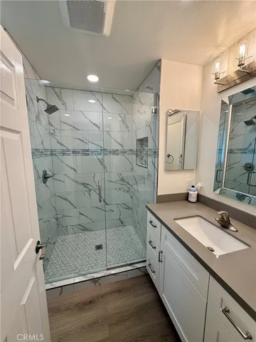 a bathroom with a granite countertop sink a mirror and shower