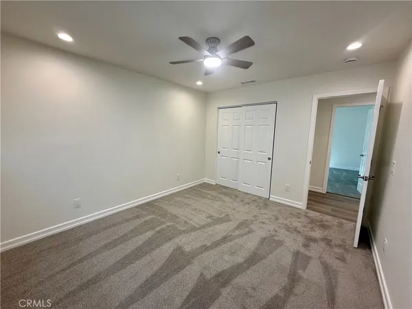 an empty room with closet and a ceiling fan