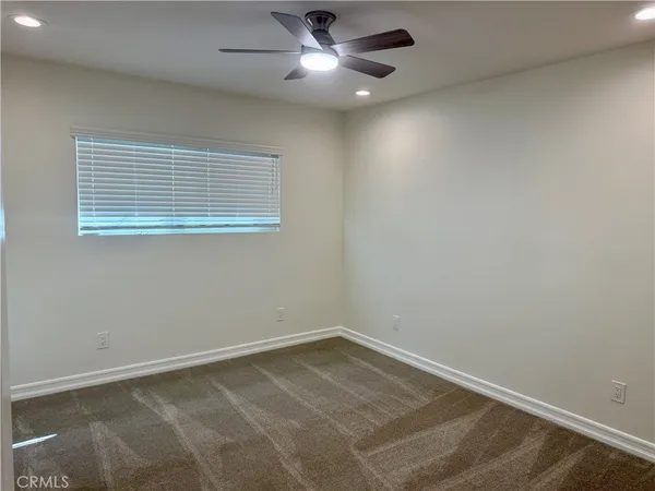 an empty room with a window and ceiling fan