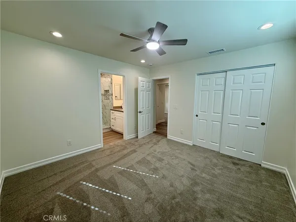 an empty room with closet and a chandelier fan