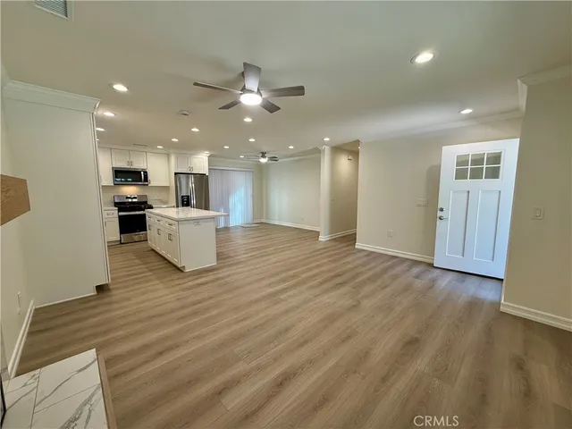 a view of kitchen with kitchen island wooden floor center island and stainless steel appliances