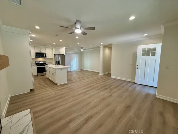 a view of kitchen with kitchen island wooden floor center island and stainless steel appliances