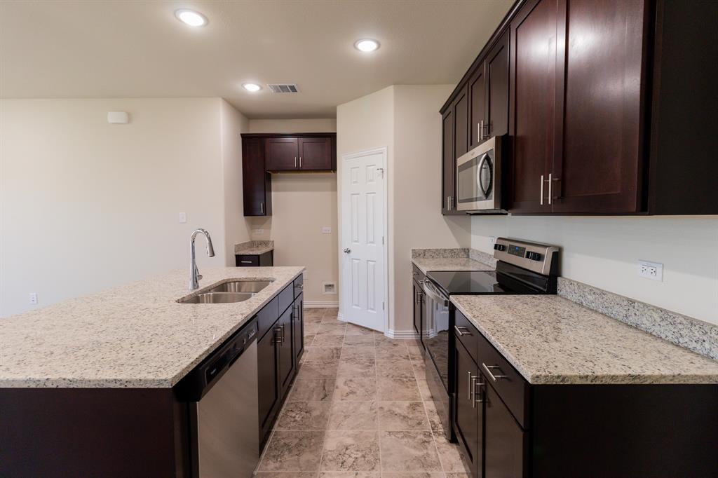 572 Ruthye Lane Pilot Point, TX 76258 - Photo 14 of 32 a kitchen with granite countertop kitchen island a sink stove and refrigerator