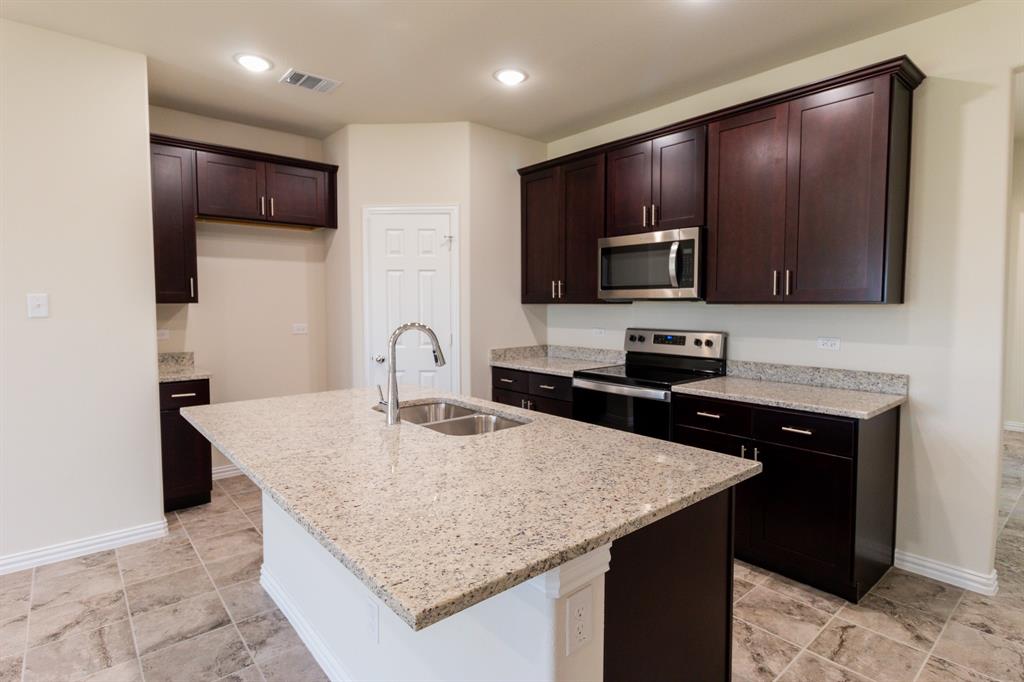 572 Ruthye Lane Pilot Point, TX 76258 - Photo 15 of 32 a kitchen with kitchen island granite countertop wooden cabinets a refrigerator and a stove