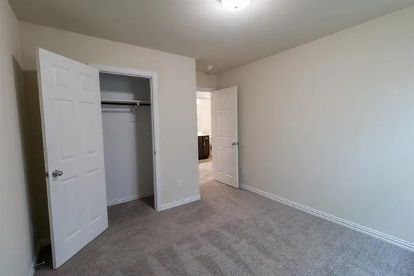 an empty room with closet and a hallway