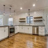 a large white kitchen with stainless steel appliances granite countertop a stove and a wooden floors