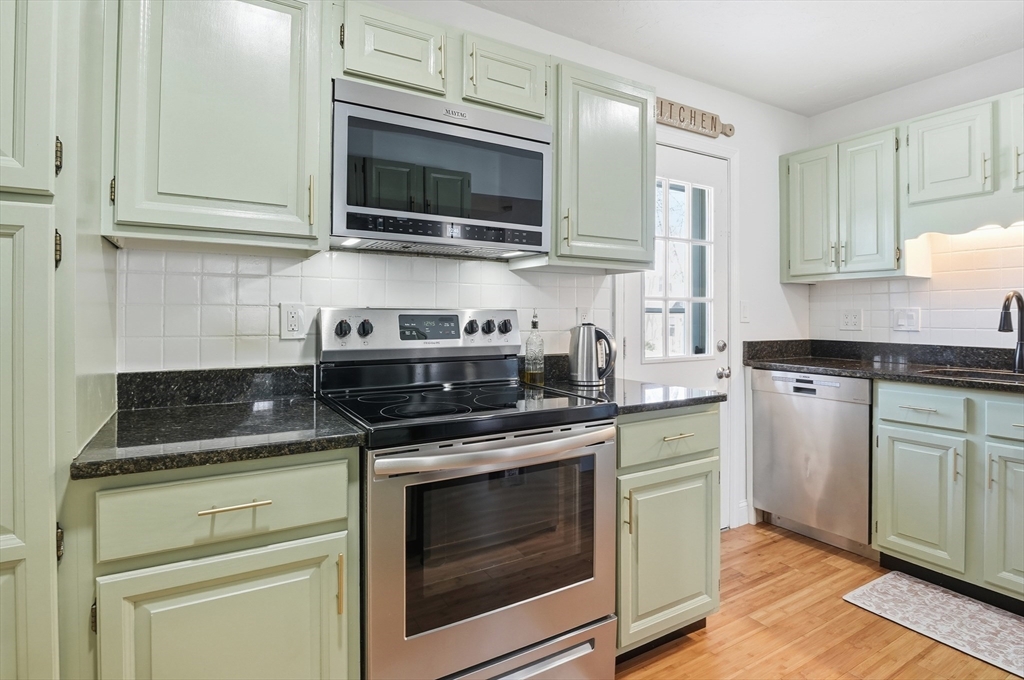 425 Main Street, Unit 21D Hudson, MA 01749 - Photo 8 of 21 a kitchen with stainless steel appliances granite countertop white cabinets granite counter tops and a wooden floors