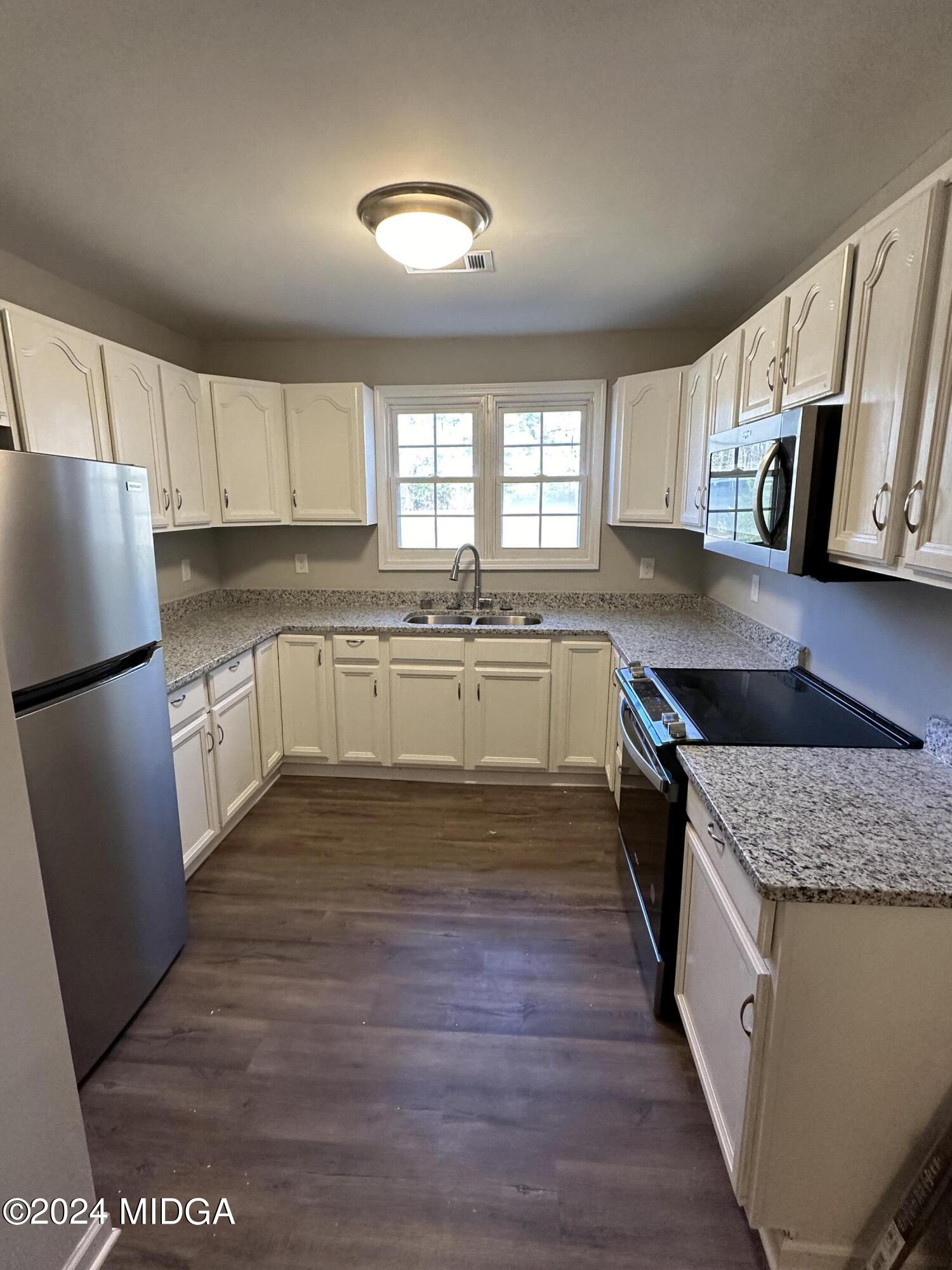 365 Taylor Road Juliette, GA 31046 - Photo 3 of 12 a kitchen with stainless steel appliances granite countertop a stove a sink dishwasher a refrigerator and white cabinets with wooden floor