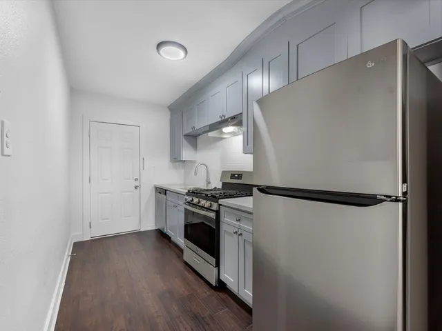 a kitchen with a refrigerator a stove and wooden floor