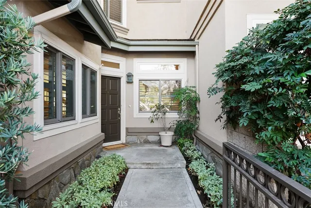 a view of a pathway of a house with potted plants and wooden fence