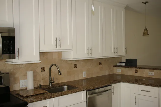 a kitchen with granite countertop white cabinets and sink
