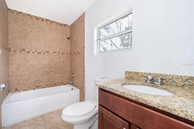 a bathroom with a granite countertop sink a toilet and bathtub