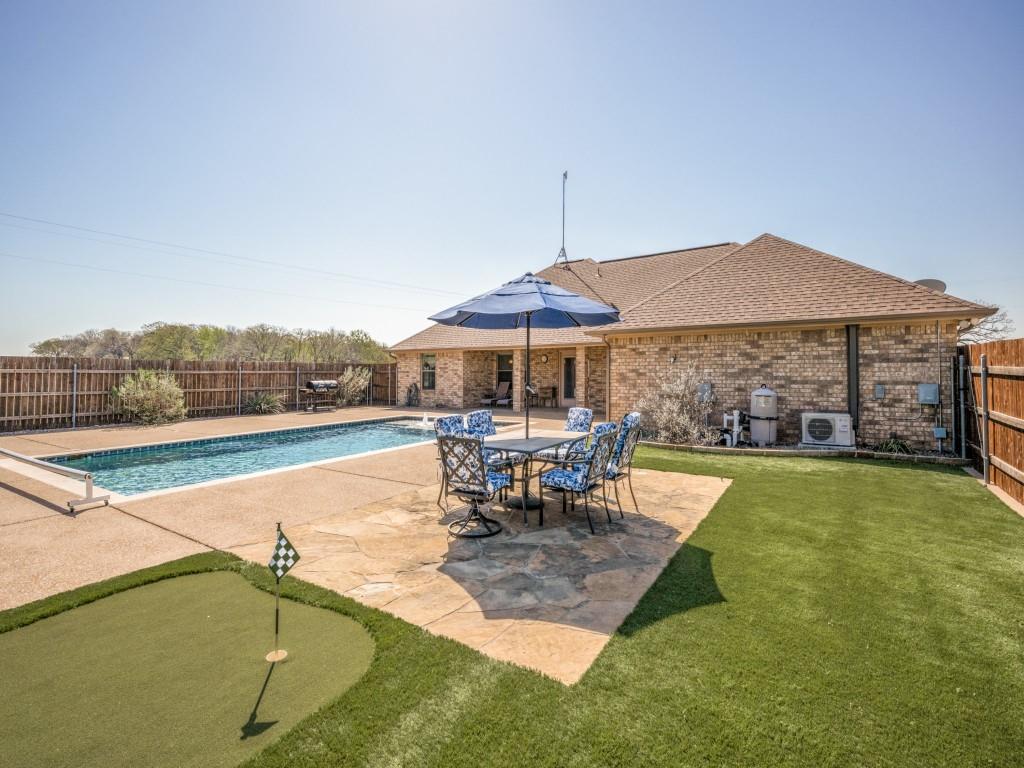 100 County Road 4181 Decatur, TX 76234 - Photo 30 of 35 a view of a swimming pool with a table and chairs under an umbrella