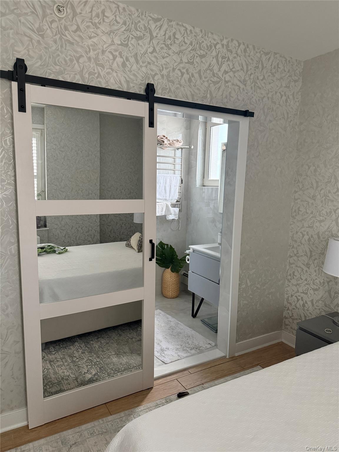 118-20 Ocean Promenade, Unit 5D Queens, NY 11694 - Photo 12 of 17 Bedroom with wood finished floors, a barn door, and wallpapered walls