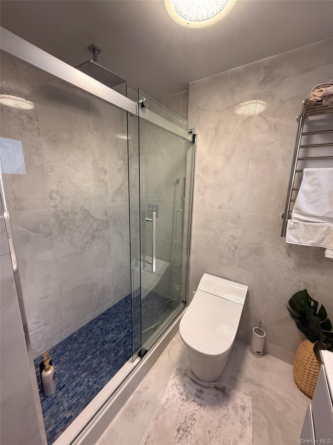 118-20 Ocean Promenade, Unit 5D Queens, NY 11694 - Photo 13 of 17 Full bathroom with tile walls, a shower stall, a towel warming rack, and marble finish flooring