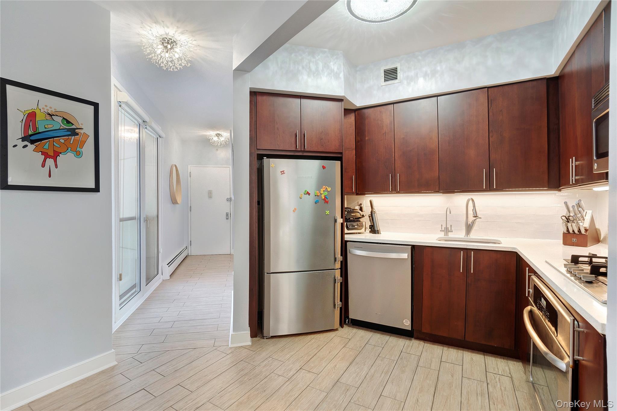 118-20 Ocean Promenade, Unit 5D Queens, NY 11694 - Photo 6 of 17 Kitchen with appliances with stainless steel finishes, light countertops, wood tiled floors, baseboard heating, and dark brown cabinetry