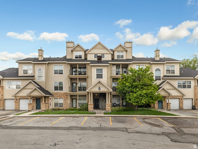 900 Bitner Road, Unit O33 Park City, UT 84098 - Photo 1 of 18 Multi-story residential building featuring light-colored siding, stone accents, multiple balconies with black railings, individual garage doors, and dormer windows