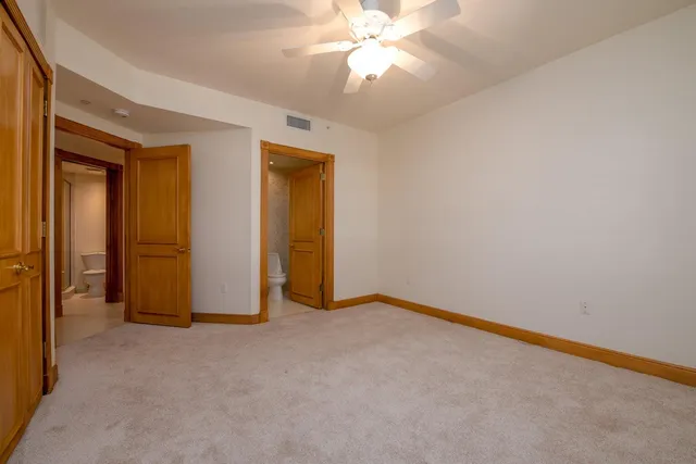 a view of an empty room with closet and a ceiling fan