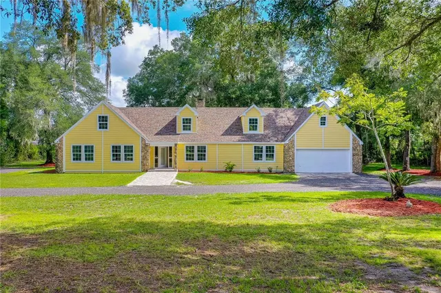 a aerial view of a house next to a big yard and large trees