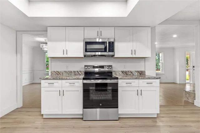 a kitchen with stainless steel appliances granite countertop a stove and white cabinets