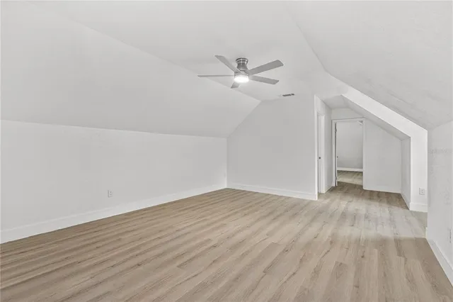 an empty room with wooden floor ceiling fan and windows