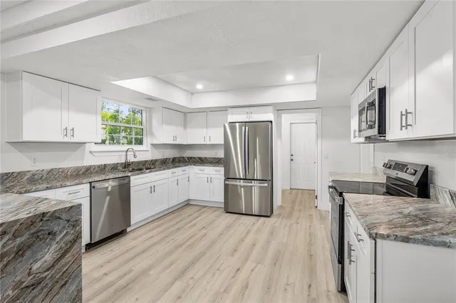 a kitchen with a refrigerator a sink dishwasher a stove and white cabinets with wooden floor