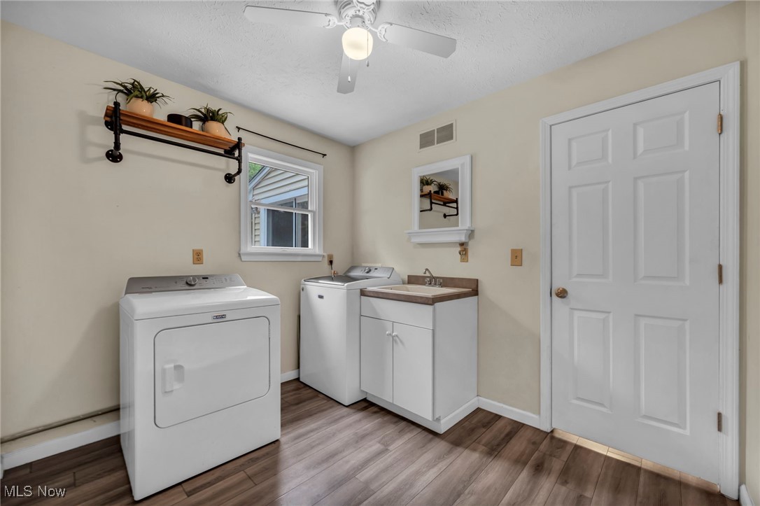 1661 Keefer Road Girard, OH 44420 - Photo 18 of 35 Main Floor Laundry room featuring washing machine and dryer, wood finished floors, a ceiling fan, cabinet space, and baseboards