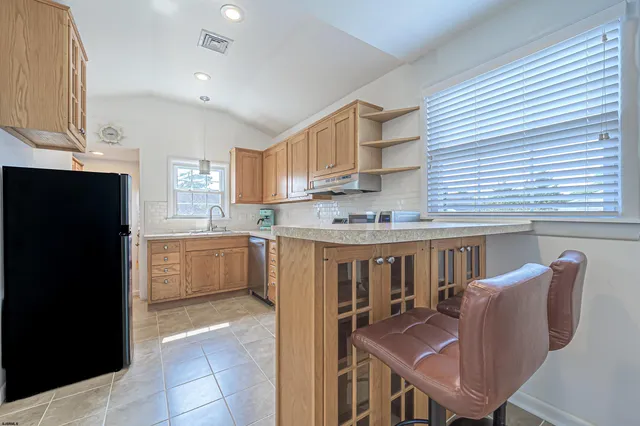 a kitchen with stainless steel appliances granite countertop a refrigerator a sink dishwasher a stove with wooden cabinets