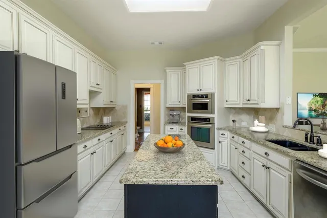 a kitchen with stainless steel appliances granite countertop a stove refrigerator and cabinets