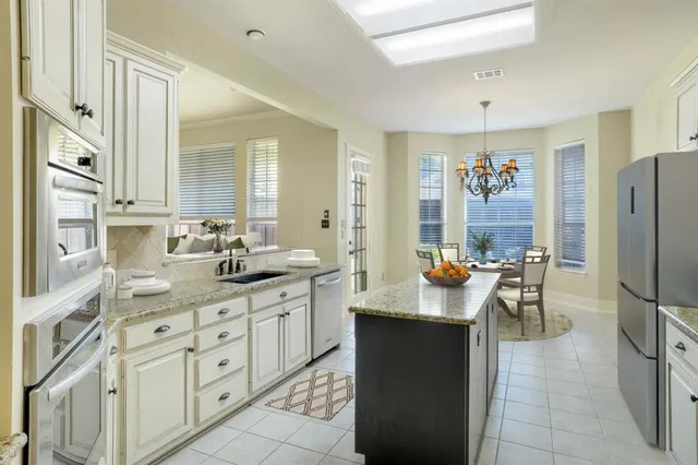 a kitchen with stainless steel appliances kitchen island granite countertop a refrigerator a sink a stove and white cabinets