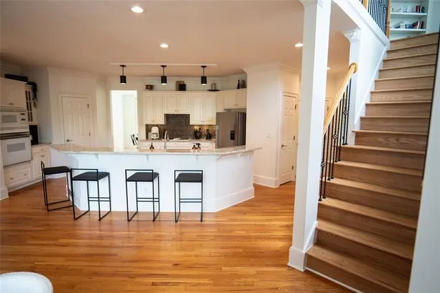 a kitchen with kitchen island granite countertop wooden floor and a view of living room