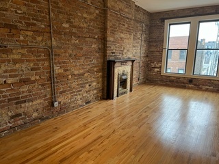 1215 West Grand Avenue, Unit 3F Chicago, IL 60642 - Photo 2 of 15 a view of empty room with wooden floor and fireplace