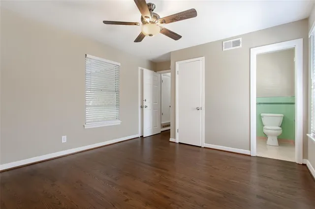 an empty room with wooden floor and a ceiling fan