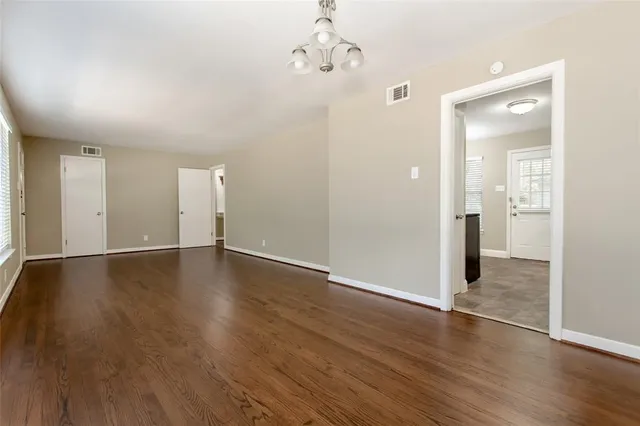 an empty room with wooden floor and mirror