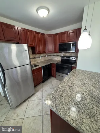 a kitchen with granite countertop a refrigerator and a stove top oven