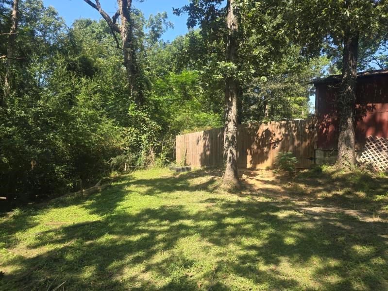 390 Campground Road Trinity, TX 75862 - Photo 19 of 37 Expansive backyard featuring a partial wood fence, mature trees, and a sloped, grassed area
