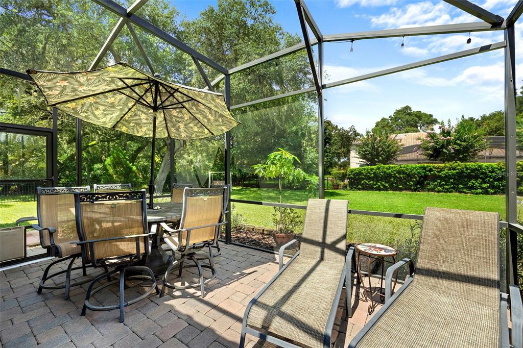 8692 Crested Eagle Place Sanford, FL 32771 - Photo 20 of 56 a view of a patio with table and chairs under an umbrella with a small yard