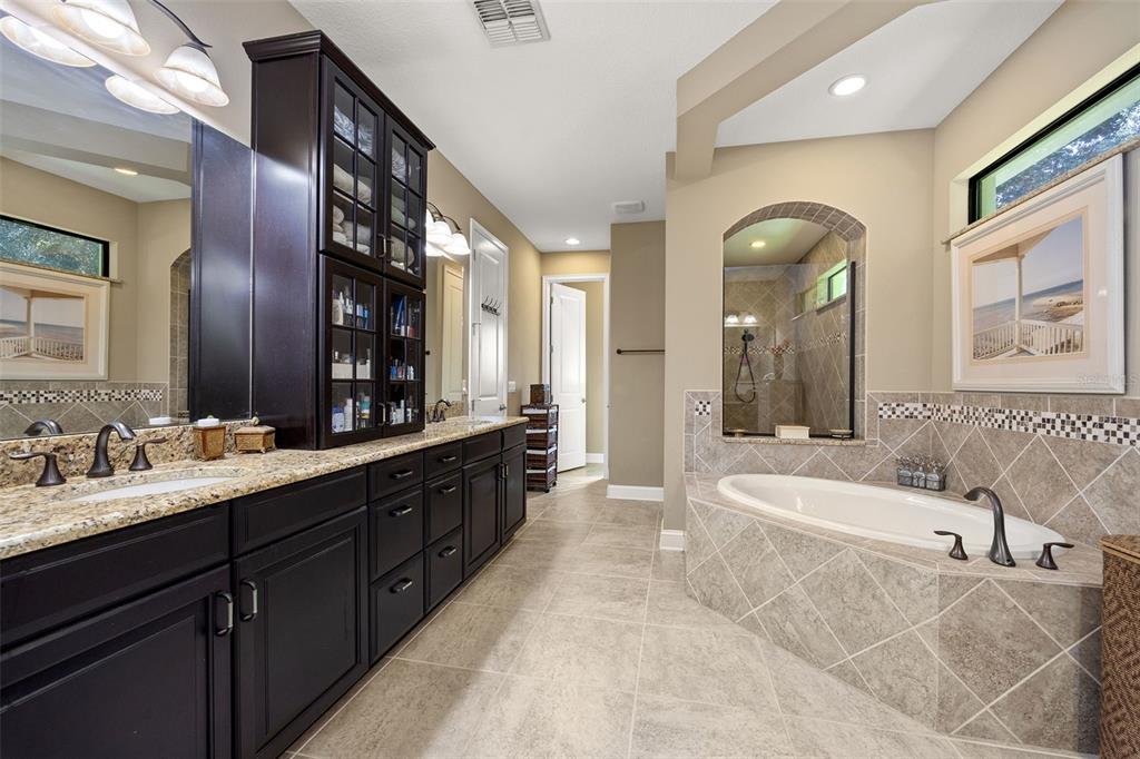 8692 Crested Eagle Place Sanford, FL 32771 - Photo 27 of 56 a bathroom with a tub a double vanity sink and mirror
