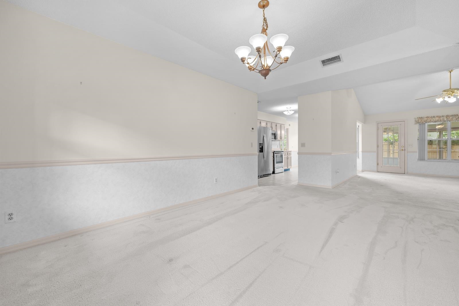512 Moultrie Wells Road St. Augustine, FL 32086 - Photo 11 of 51 Empty room featuring light colored carpet, a chandelier, ceiling fan, and lofted ceiling