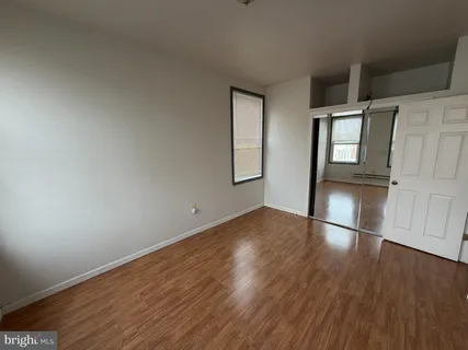 an empty room with wooden floor and entrance