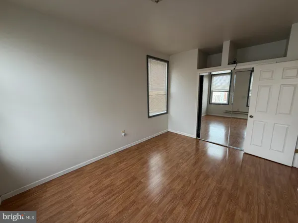 an empty room with wooden floor and entrance