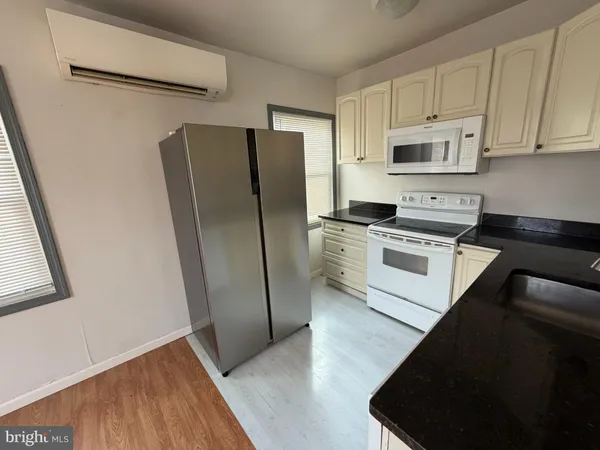 a kitchen with stainless steel appliances granite countertop a refrigerator a stove a sink and white cabinets with wooden floor