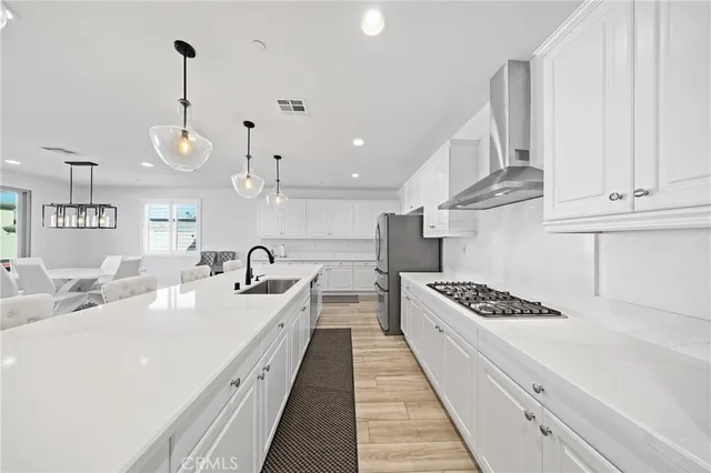 a large kitchen with kitchen island a stove a sink dishwasher and a fireplace with wooden floor