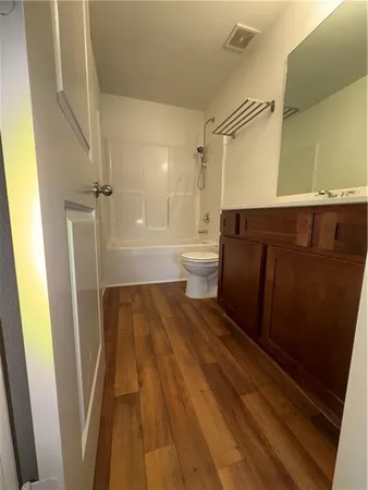 an empty room with wooden floor ceiling fan and windows