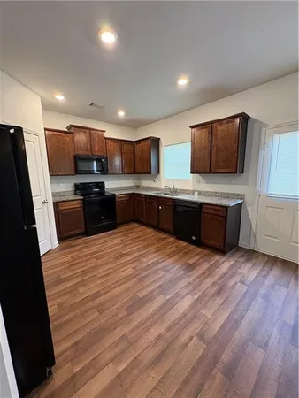 a large kitchen with stainless steel appliances a stove a refrigerator a sink a microwave oven and a refrigerator with wooden floor