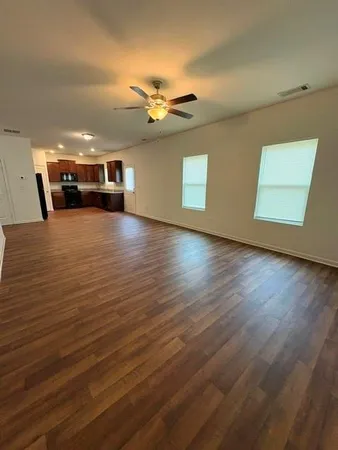 a view of a livingroom with a flat screen tv wooden floor and a ceiling fan